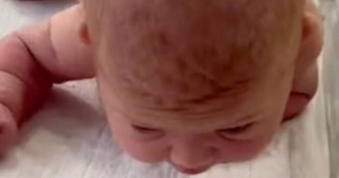 Newborn baby crawls across the hospital cot